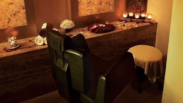 Image of  a hair cut session with lit up candles and a chair at IOSIS Spa & Wellness Guwahati