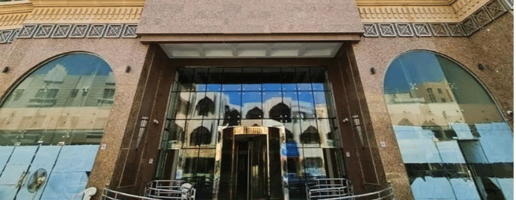 Facade view of La Maison Hotel, Doha from below with blue sky in the background.