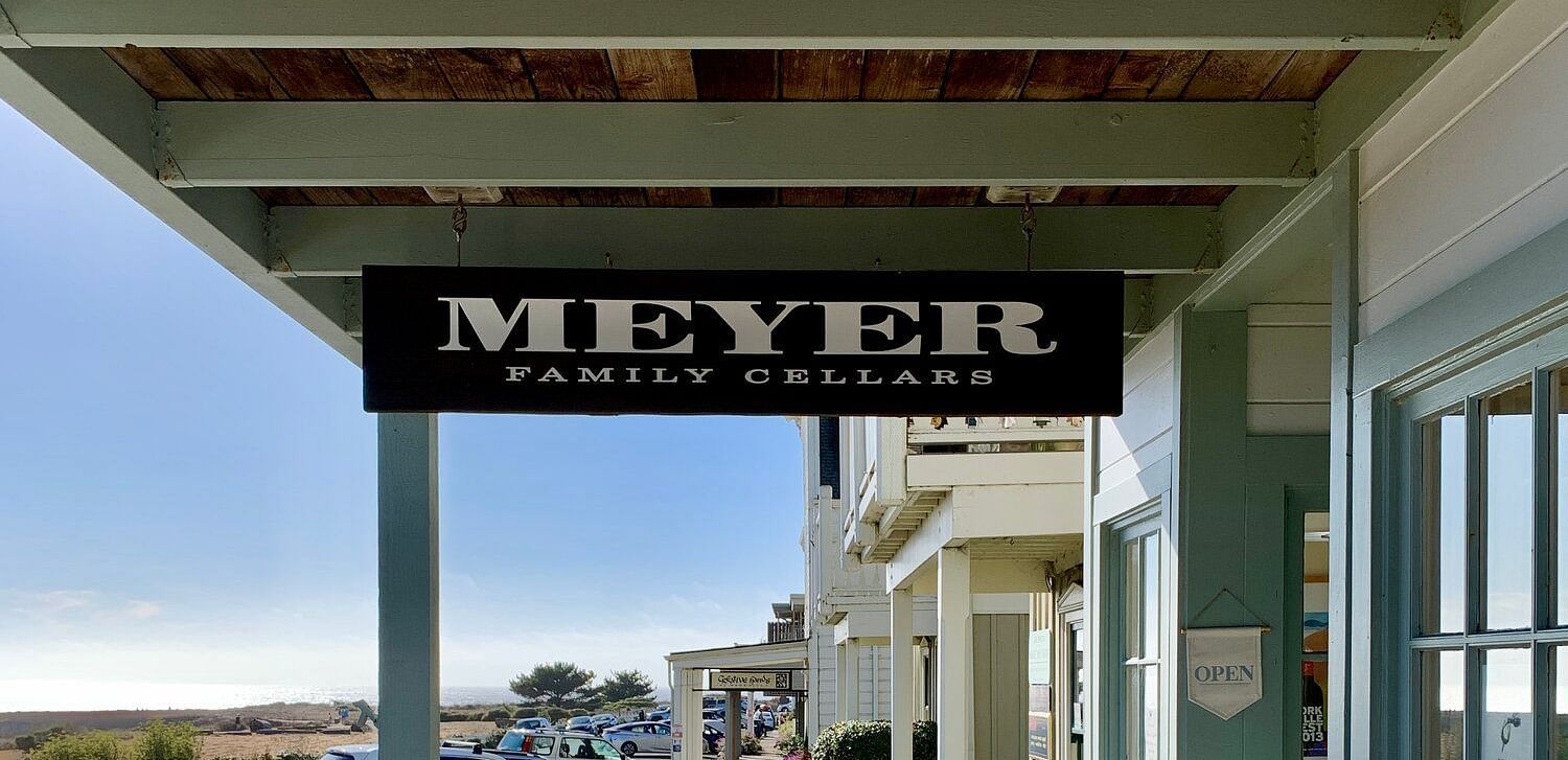 The Meyer Family Cellars tasting room entrance features a wooden deck, signage, and a glimpse of parked cars.