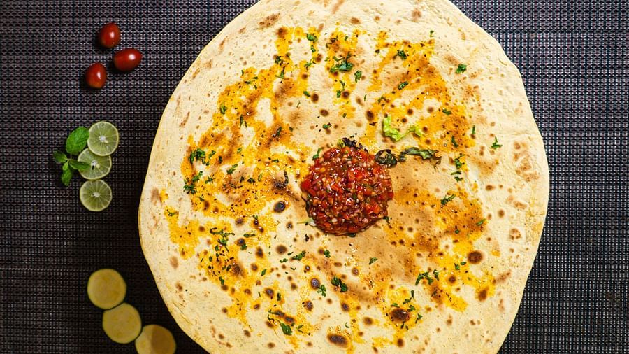 Flatbread with various toppings on a dark surface.