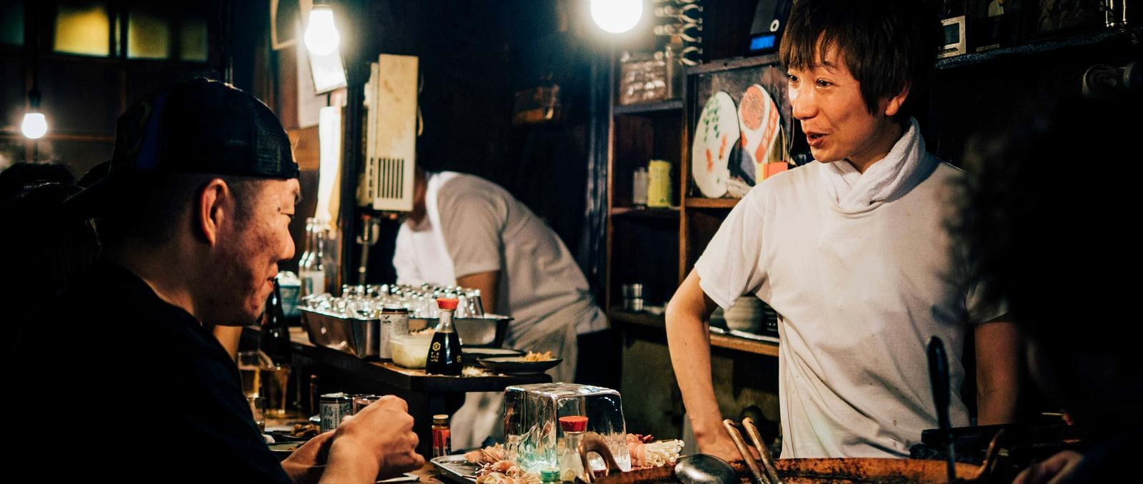 A chef in a stall with delicacies laid on a table
