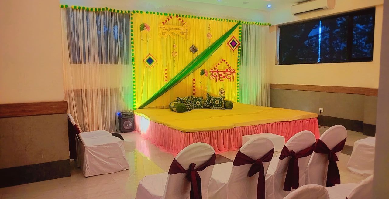 Banquet hall setup with rows of chair and a stage decorated with yellow clothing  at Max Hotel Prayagraj.
