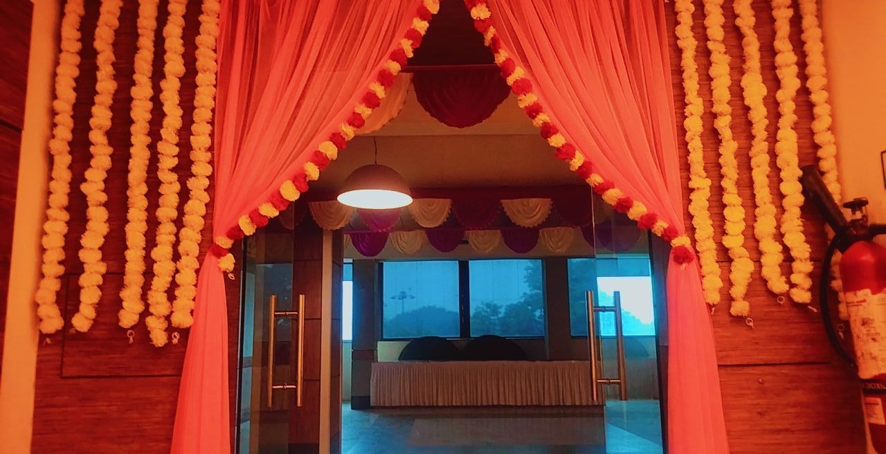 Banquet entrance decorated with orange marigold garlands and red drapes at Max Hotel Prayagraj.