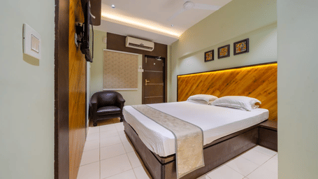 Spacious bedroom with a double bed, wall arts, an A/C, a seating area, and modern lighting – Hotel Dolphin Puri