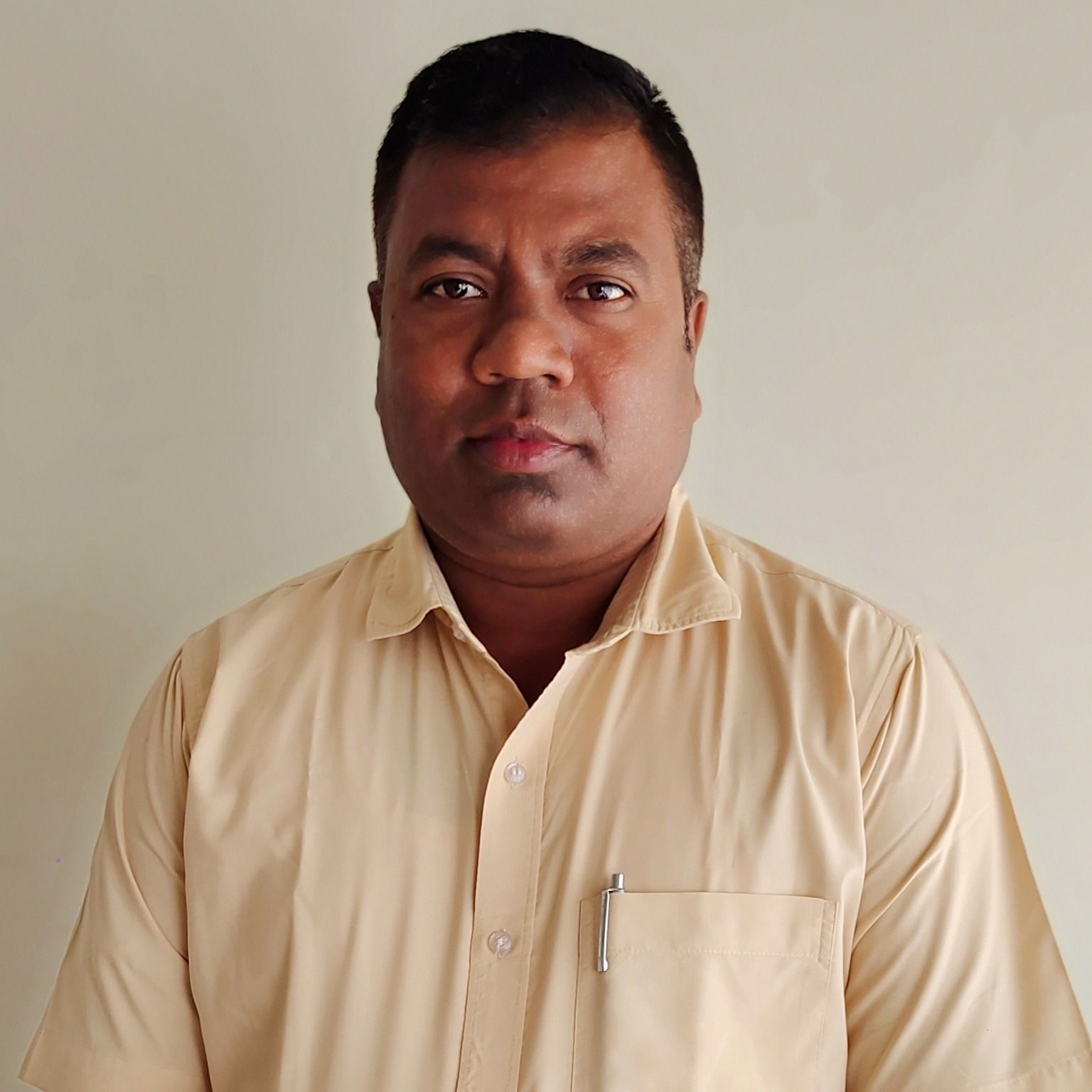 A man with a short haircut and a light-colored collared shirt looks directly at the camera