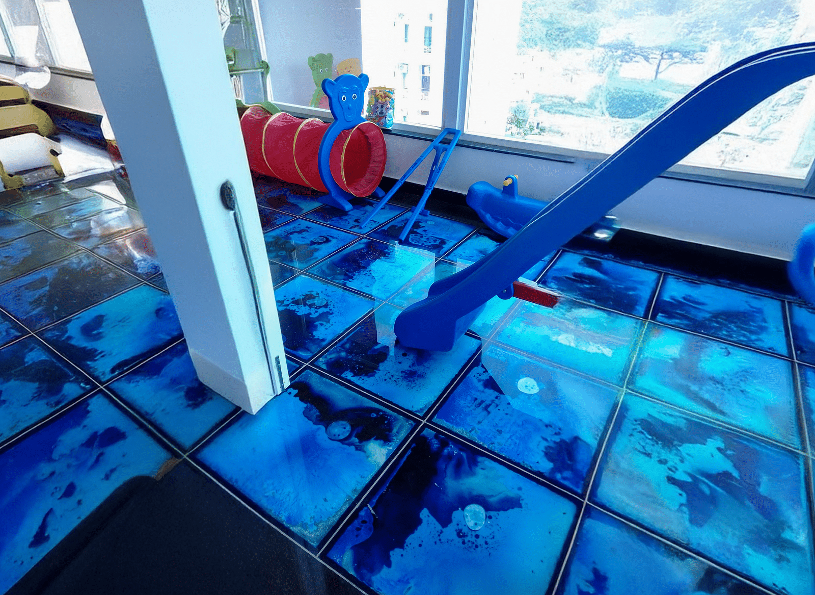 The Kids' Play Area with blue tiles featuring indoor activities for toddlers at Regenta Inn DLS.