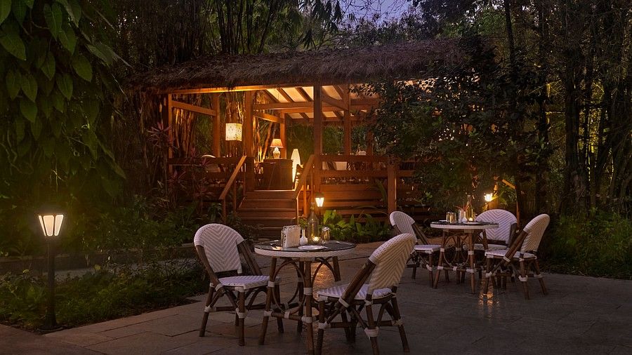 Night view of an outdoor dining area with chairs around tables and a cabin in the background.