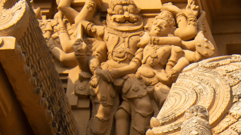 A view of Brihadeeswarar Temple's gopuram having a carving of deity having numerous hands holding another person in a headlock. It is one of the places of interest in Tanjore, for historical and architectural significance.