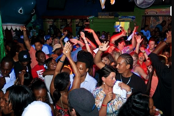 A group of people dancing through the night in a street - Hotel 39, Jamaica