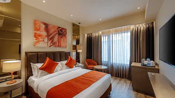 An image of a bedroom featuring a double size bed, a bedside table, a desk, a flat TV screen and much more - HOtel Saket 27