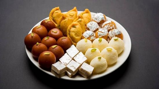 A plate of assorted Indian sweets including gulab jamun and barfi.