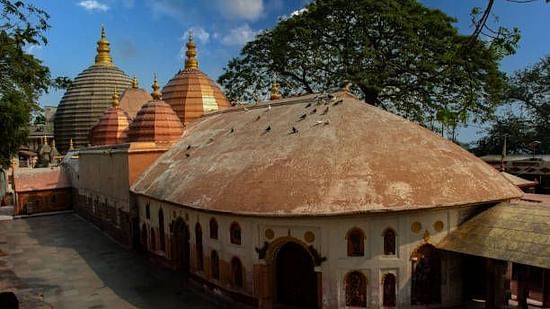 Historic Kamakhya Temple complex with domed structures, nestled among trees, radiating cultural heritage under bright daylight in Guwahati.