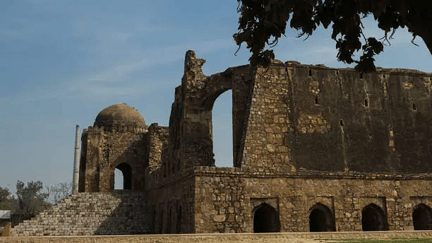 Remains of a historic fort or monument with arched stone structures and open lawn.