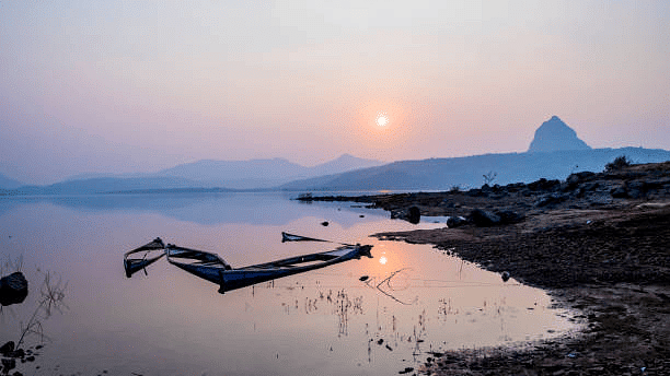 Serene lakeside view at sunset with boats resting along the shoreline.