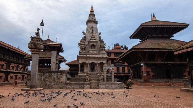 Pigeons gathering in front of the ancient stone Krishna Mandir and pagoda temples at Patan Durbar Square in Lalitpur, Nepal.
