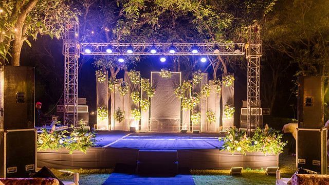 alt-text Illuminated stage with lighting and floral arrangements.