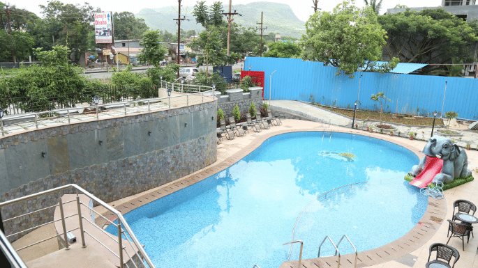 An image of a swimming pool and beside it there are seating area - VITS Lonavala.