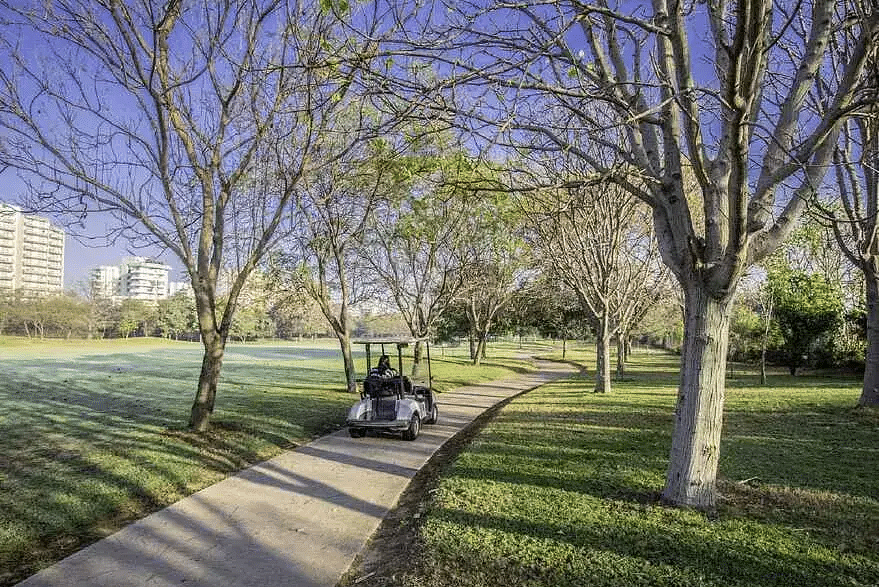 A golf cart on a tree-lined path with two people at Karma Chalets.