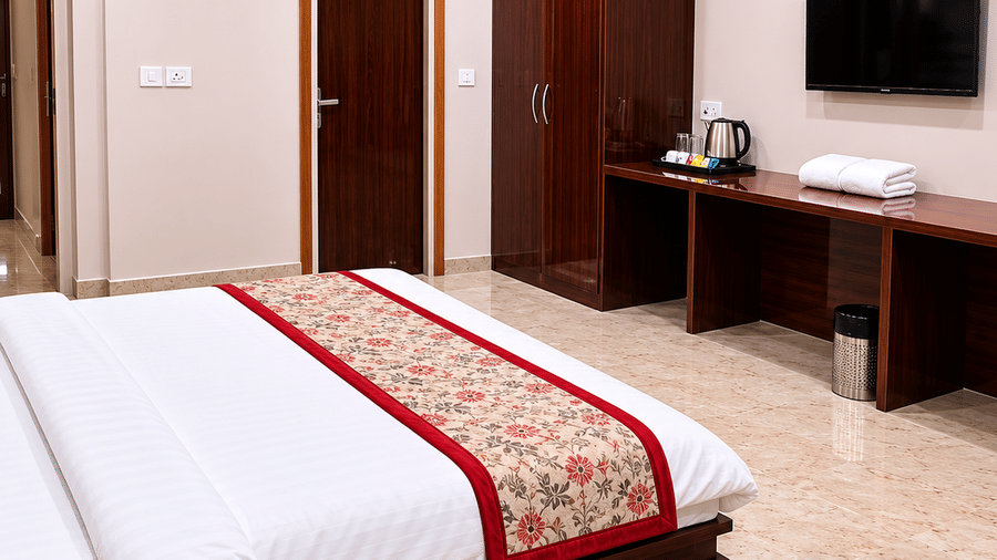 Guest room with bed, television and wooden furnishings at Bamboo Saa Mulberry Resort, Pushkar.