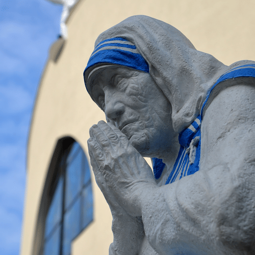 a statue of Mother Teresa with a building in the background