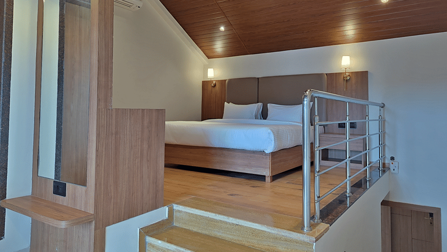 Bedroom with a double bed, wooden furnishings, loft area, and railing.