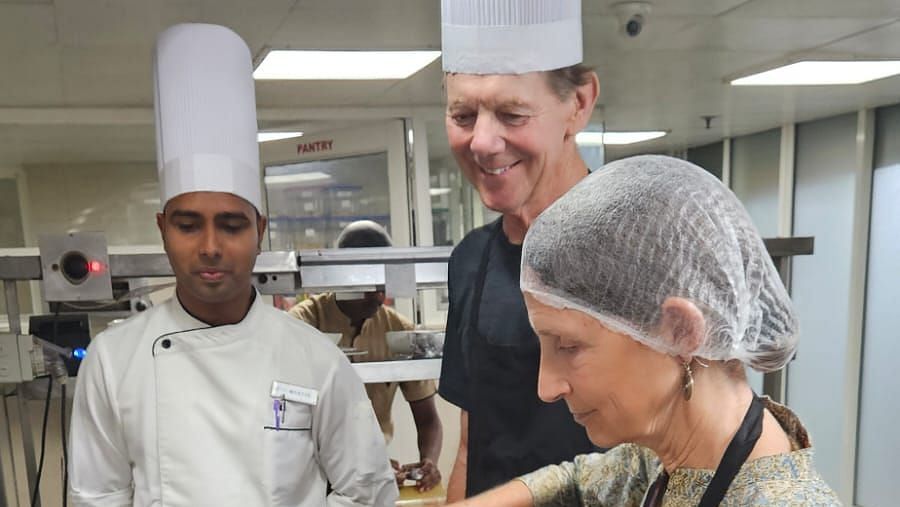 Cookery session with a chef cooking while two other chefs oversee the process