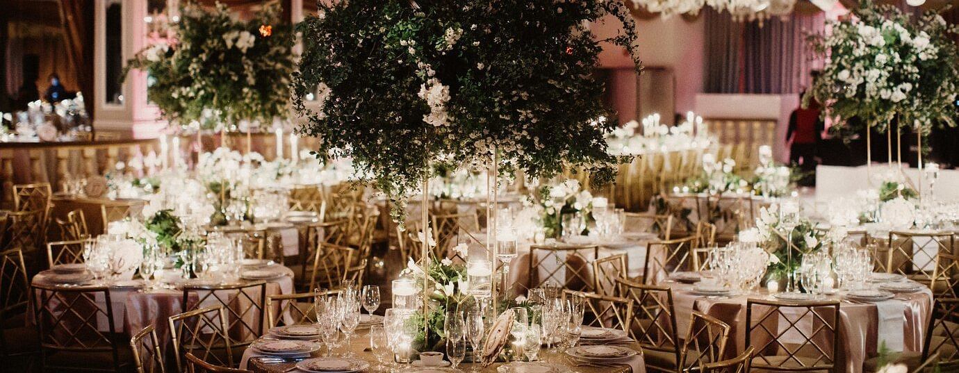 Elegant indoor wedding reception with floral decorations, chandeliers, and set tables, emphasizing a luxurious celebration.