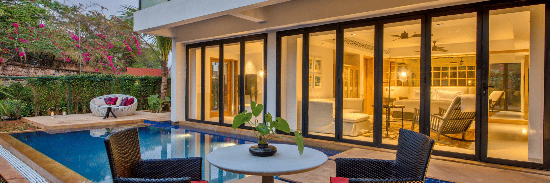 A view of the sit out area near the private pool of an Azaya XL Pool Suite with ceiling to floor windows on the building next to the pool at Azaya Beach Resort, Goa, A South Goa stay near the beach.