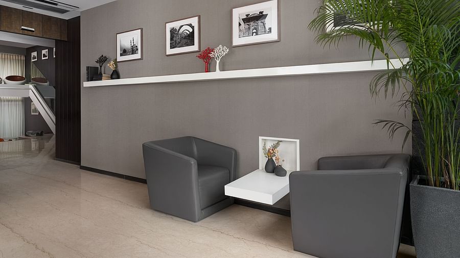 A contemporary lobby at The Atara, Gurugram presents a sleek reception desk, comfortable armchairs, decorative wall art, and a vibrant green plant 