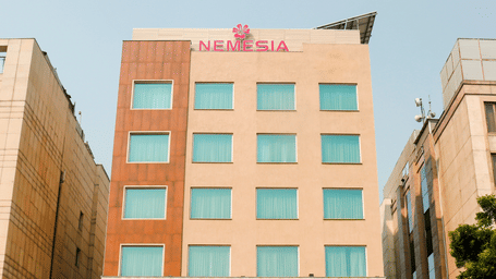 Facade of the Nemesia City Center in Gurugram featuring the hotel's entrance and its surrounding greenery.