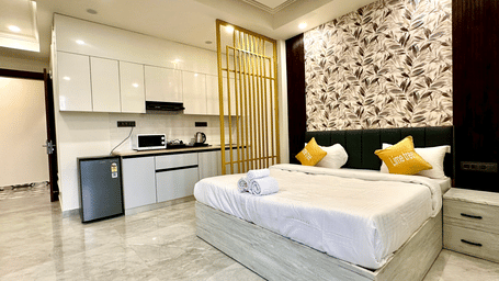 Suite of Lime Tree Hotels & Service Apartment Private Limited featuring an open kitchen, a bed, and patterned wallpaper.