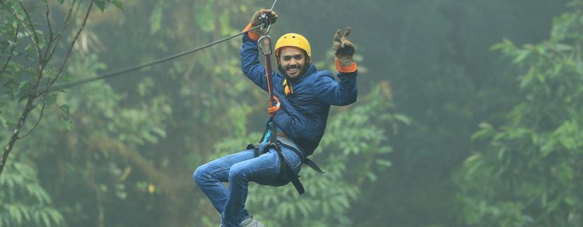a person doing zip lining with greenery in the background - Stone Wood Jungle Resort, Dandeli