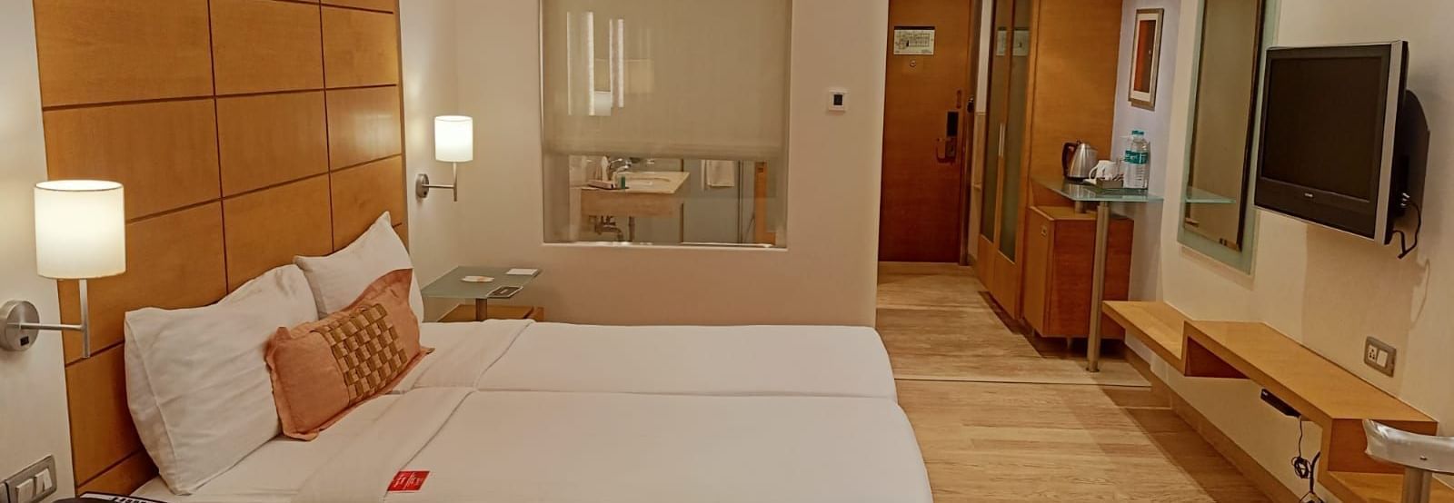 Image of twin beds in the executive twin room at our hotel featuring a flat screen television, bed side table, mirror, and other furniture. | Mirage Hotel