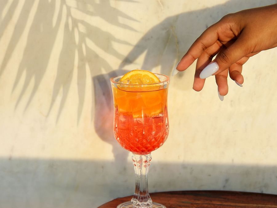 A hand reaching for a refreshing mocktail in a glass.