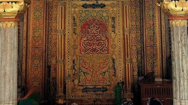 Ornately decorated interior space with intricate carvings and a hanging lamp.
