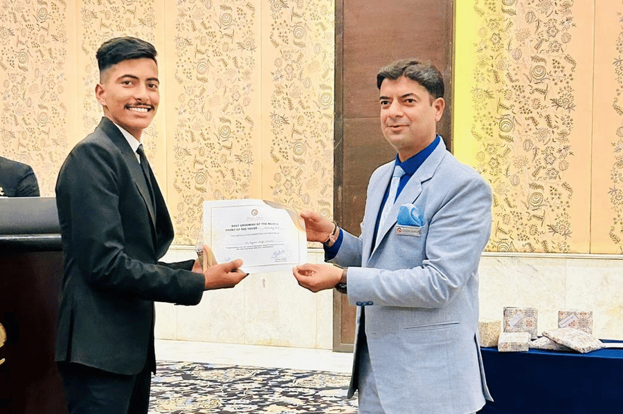 A person receives a certificate from another individual during a ceremony. They stand on a carpet.
