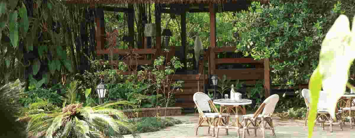Thatched-roof pavilion with outdoor seating surrounded by lush plants at Amanvana Spa Resort, Coorg.