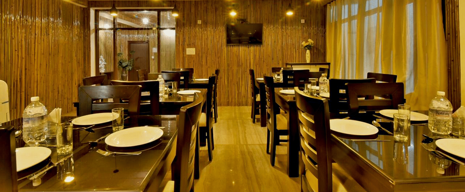 A shot of the woodden tables and chairs inside the restaurant at the resort | DLS Kapoor Resort Manali