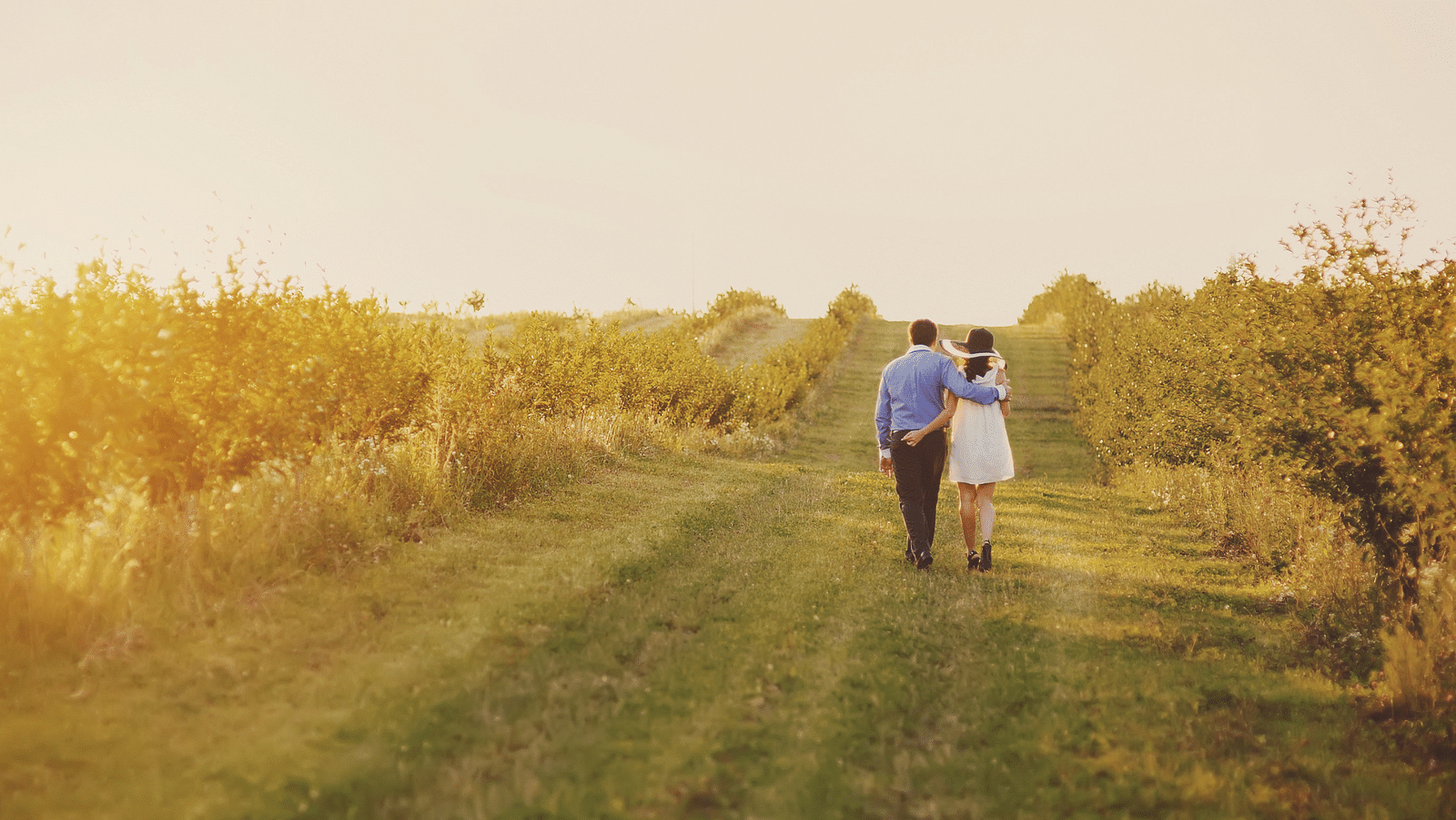 an image of a couple walking on a field holding hands together