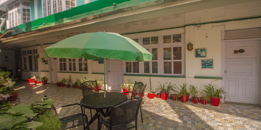 A dining set up with chair and table outside a building with an umbrella in the centre