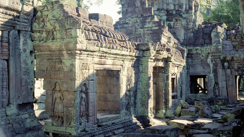The weathered stone entrance and pillars of an ancient Hindu temple surrounded by trees at Ananta Express, Katra.