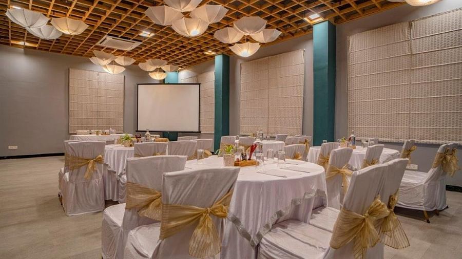 Indoor banquet hall setup with round tables and decorative ceiling at Golden Tulip, Udaipur.