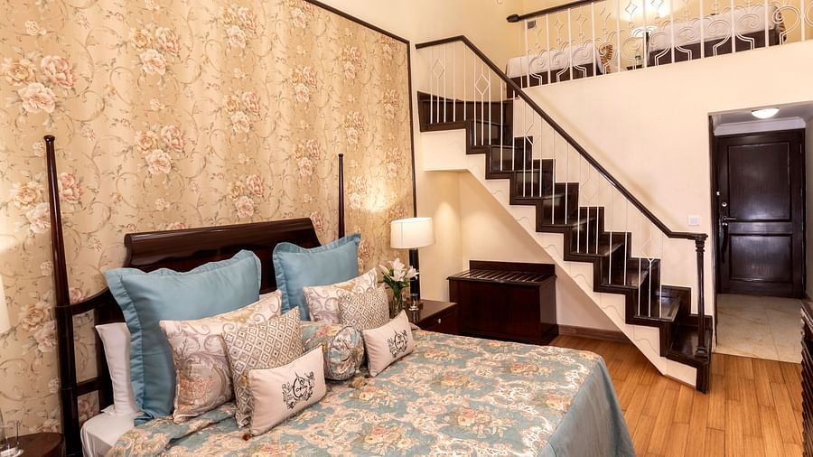 image of a king size bed with a staircase going up at Duplex Family Suite at The Claridges Nabha Residence