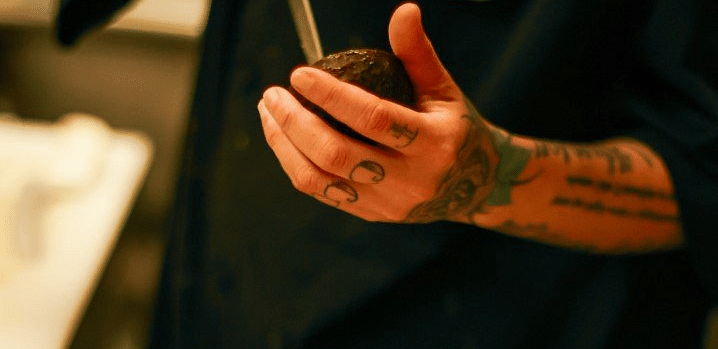 A person in dark clothing holding a platter of small dishes or appetizers.