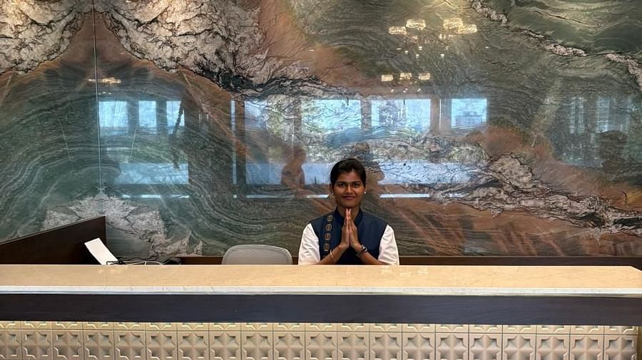 A reception desk with a patterned front and a person standing behind it is visible in a warmly lit interior - Melior Inn