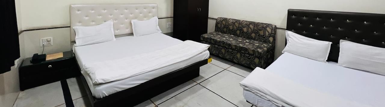 A family room at Ajay Guest House with multiple beds and a seating area, designed to accommodate families or groups comfortably.