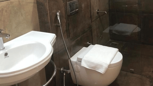 A rustic-style bathroom with warm tones, featuring contemporary fixtures. - Abad Brookside Lakkidi, Wayanad