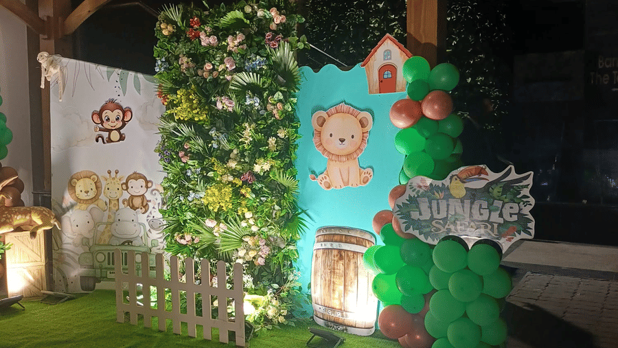 Whimsical kids-themed event decor at The Piccadily featuring a lush green backdrop, illustrated storybook characters, fairy lights, and a garden-style setup.