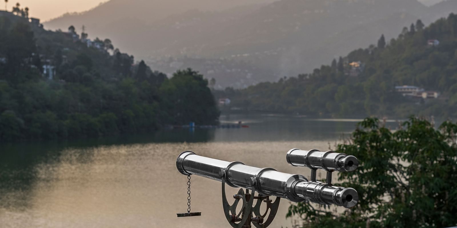 binoculars set up near a picturesque lake, with hills in the background, ideal for nature observation.