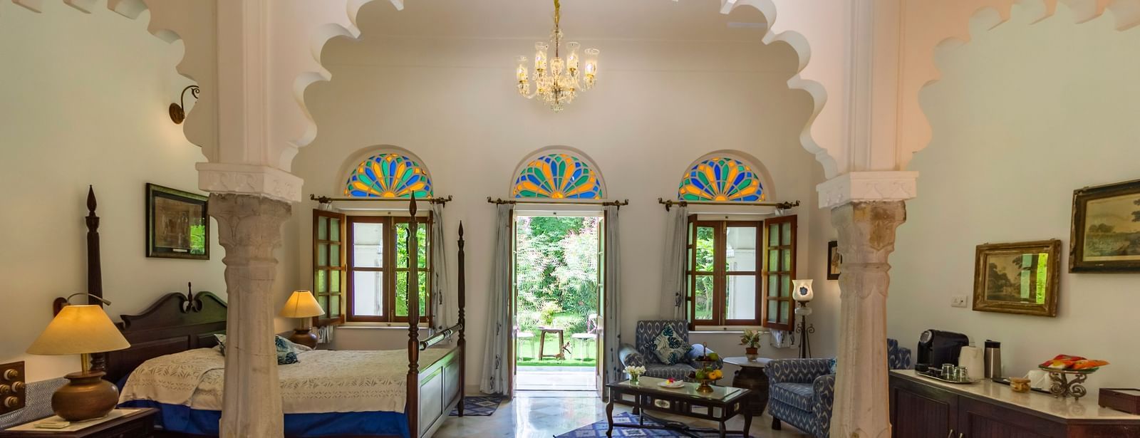 image of the Deluxe suite at Dev Shree, deogarh through the arched pillars featuring a double bed